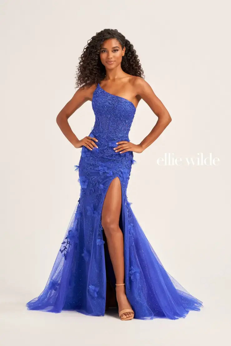 This Ellie Wilde EW35049 prom dress is designed with sheer shimmer lace, a one shoulder sheer lace corset bodice, and a mermaid silhouette with a backless design and a thigh-high slit. Perfect for prom or any formal occasion, this gown offers a touch of elegance and glamour, sure to turn heads and make a lasting impression. backless lace up  Sizes: 00-16  Colors: Emerald, Dark Red, Royal Blue