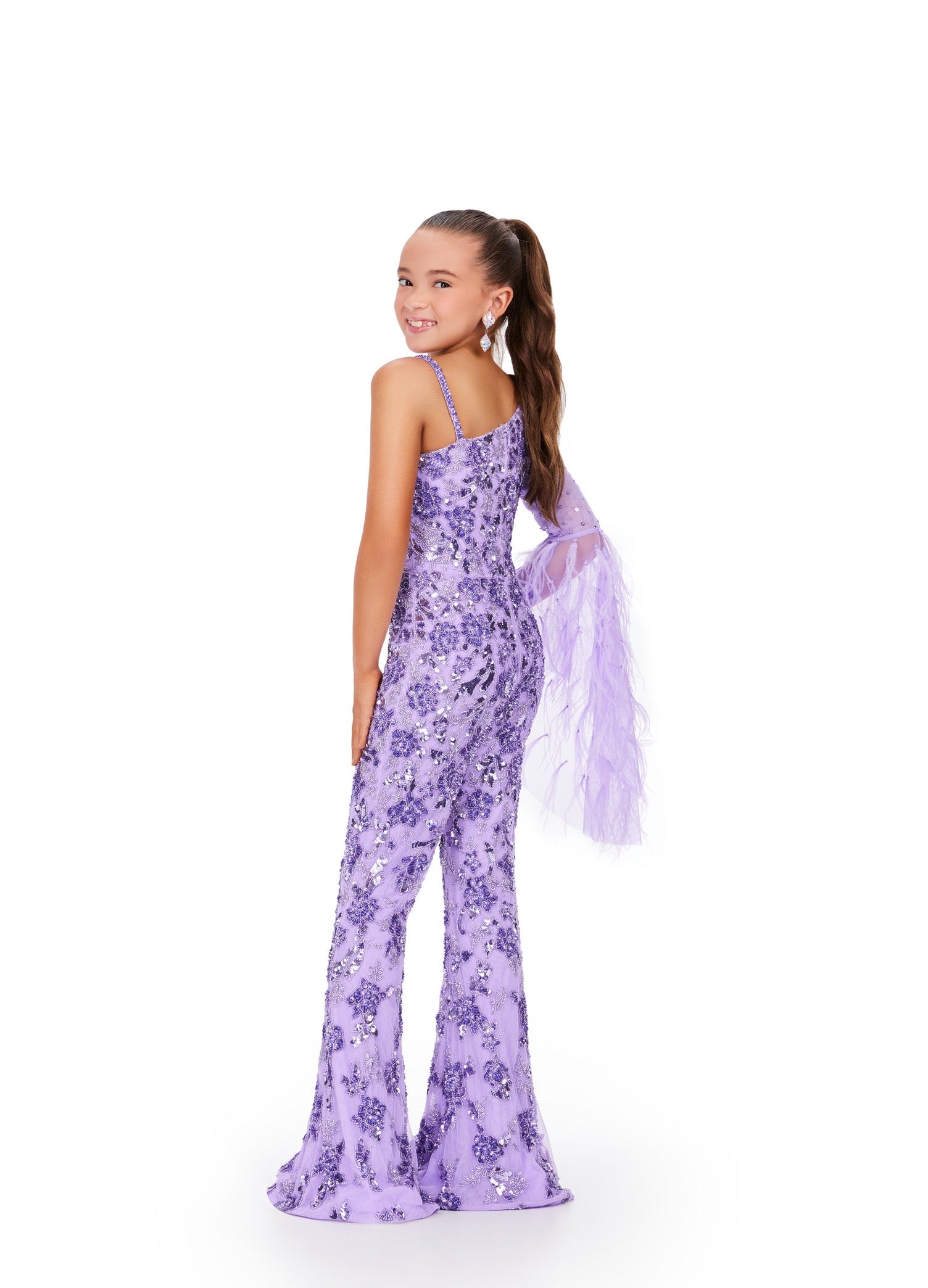 The Ashley Lauren Kids 8268 Girls Beaded Pageant Jumpsuit is a must-have for any fashion-forward young lady. Adorned with intricate beadwork and featuring dramatic feather bell sleeves, this jumpsuit will make her feel like a true fashionista. Perfect for pageants or any special occasion, it's both stylish and fun. This one shoulder kids jumpsuit features an intricate bead pattern throughout. The look is complete with a bell-sleeve scattered with feathers.