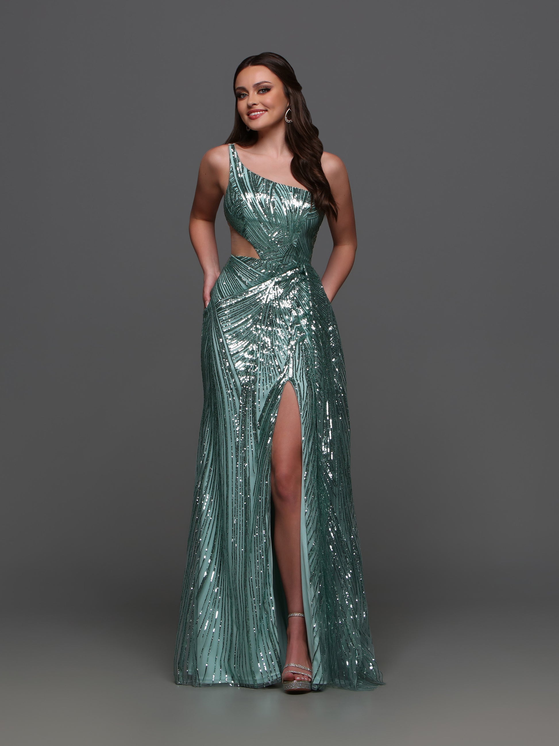 Elevate your formal look with the Candice Wang 72323 Sequin One Shoulder Cutout Dress. The sequin detailing adds a touch of glamour while the one shoulder and cutout design creates a sophisticated silhouette. The overskirt and maxi slit add a modern twist to this classic gown.  Sizes: 0-16  Colors: Sage