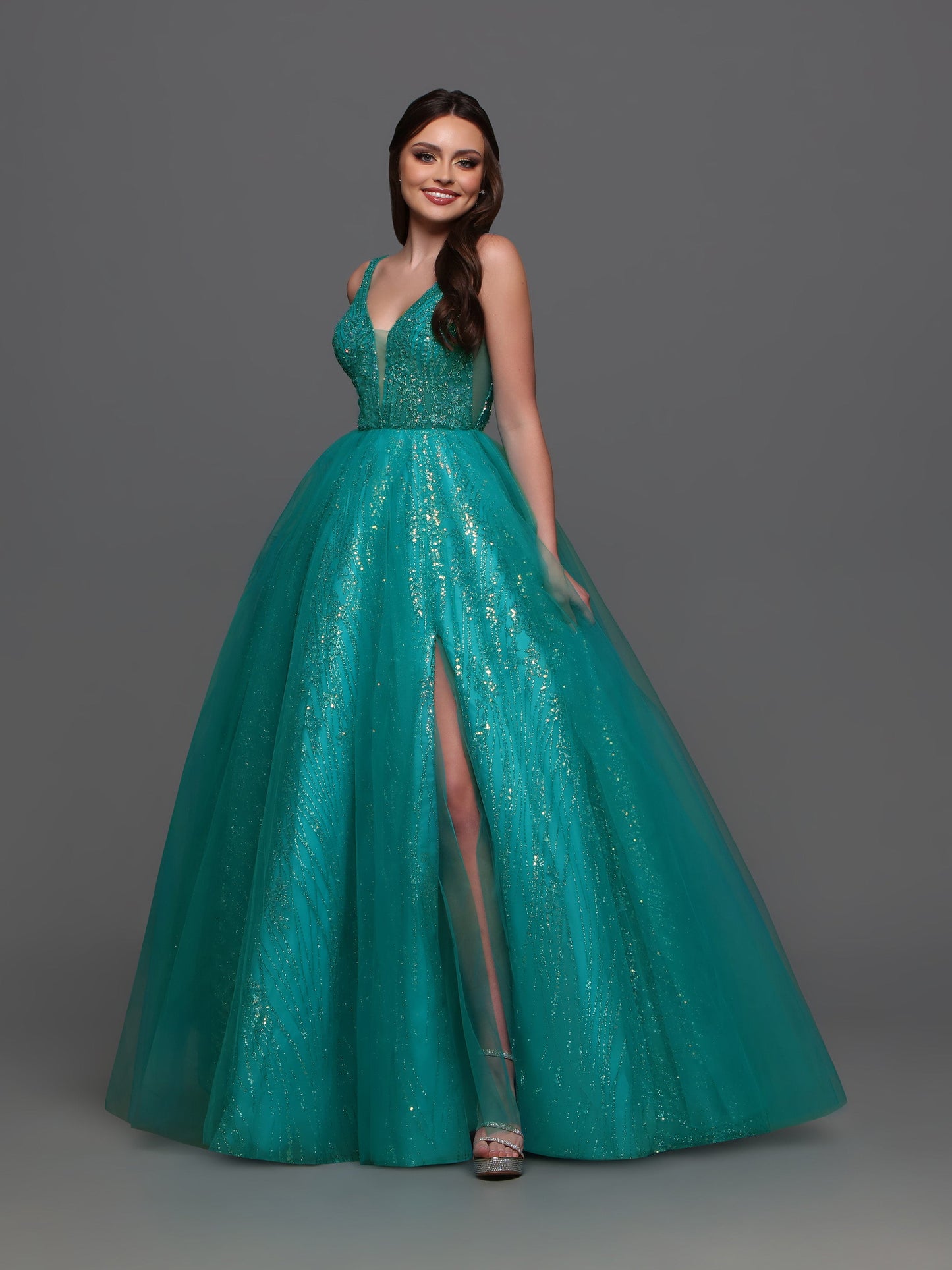 The Candice Wang 72336 Prom Dress is both chic and glamorous! Featuring a sheer glitter A-line design with a striking V-neckline and a stylish slit, this dress adds a touch of shimmer to your formal event. Perfect for making a statement and standing out in the crowd.  Sizes: 0-20  Colors: Lavender, Teal