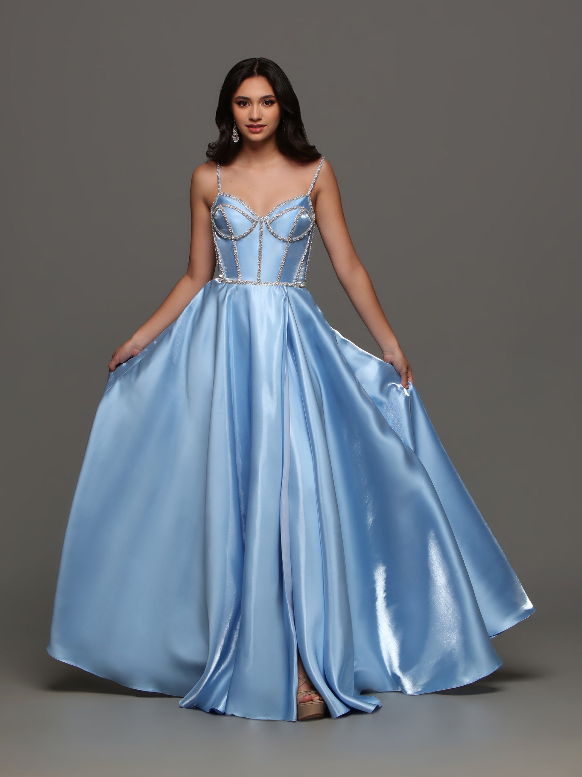Experience elegance and glamour with the Candice Wang 72398 A Line Satin Maxi Slit Ballgown. The corset top features intricate crystal detailing, while the flowing satin skirt boasts a thigh-high slit. This dress is perfect for prom, formal events, or any special occasion. Add a touch of luxury to your wardrobe. Pockets  Sizes: 0-16  Colors: Light Blue, Red