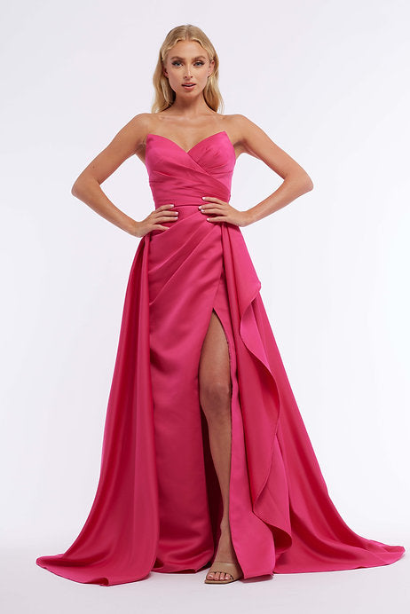 The Vienna Prom 7898 Long Prom Dress is a stunning choice for any formal occasion. With a strapless fitted bodice, ruching detail, and an elegant overskirt, this dress will flatter any figure. The high slit adds a touch of glamour while still maintaining a sophisticated look. Walk into your prom or pageant with confidence in this beautiful gown.