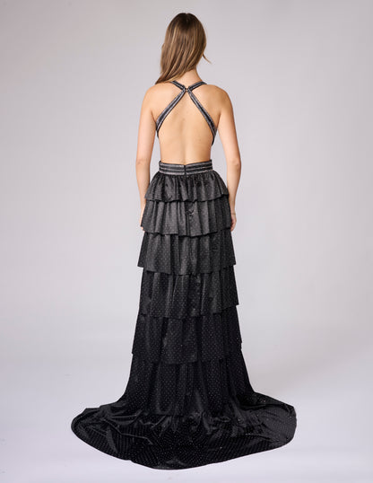 Nina Canacci's 9200 is a show-stopping pageant gown that combines elegance with contemporary flair. The crystal-layered jersey skirt features intricate micro crystal embellishments that catch light beautifully, while strategic side cutouts add modern sophistication. A dramatic maxi slit and flowing train create movement and grandeur, making this dress ideal for prom, pageants, and formal competitions. The jersey construction ensures comfortable wear throughout the evening while maintaining a polished silhou