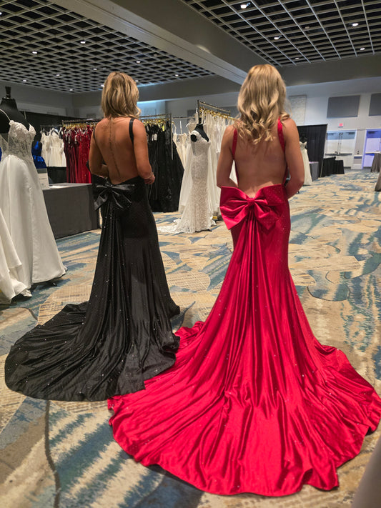 Make a stunning entrance in this Nina Canacci 9212 prom gown, expertly crafted from luxurious crystal-studded jersey. The backless silhouette showcases elegant lines while the detachable oversized bow adds dramatic flair. A removable overskirt transforms the mermaid base into a sophisticated formal statement piece. Perfect for prom, pageants, or black-tie events, this gown combines timeless elegance with contemporary design details that command attention.

Sizes: 0-14

Colors: Sky Blue, Red, Black