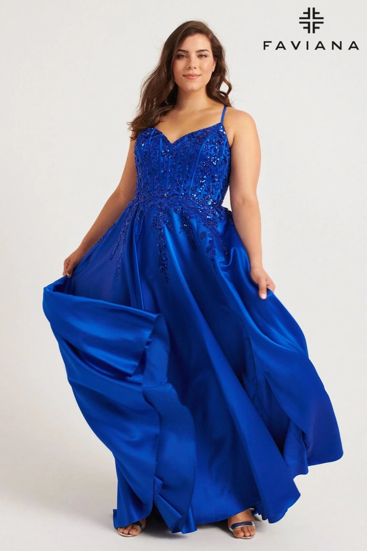 Turn heads with the Faviana 9575, a bold plus-size prom gown designed to captivate. This royal satin dress features a structured corset top adorned with shimmering sequins and delicate lace, accentuating your curves with confidence. Functional pockets add modern ease without sacrificing glamour, making it perfect for those who dare to shine all night. Step into this statement piece and own every moment of your formal occasion.

Size: 20W

Color: Royal