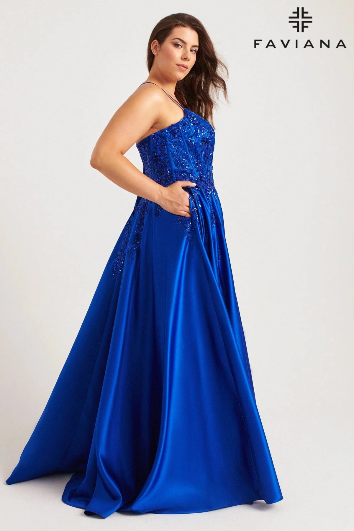 Turn heads with the Faviana 9575, a bold plus-size prom gown designed to captivate. This royal satin dress features a structured corset top adorned with shimmering sequins and delicate lace, accentuating your curves with confidence. Functional pockets add modern ease without sacrificing glamour, making it perfect for those who dare to shine all night. Step into this statement piece and own every moment of your formal occasion.

Size: 20W

Color: Royal