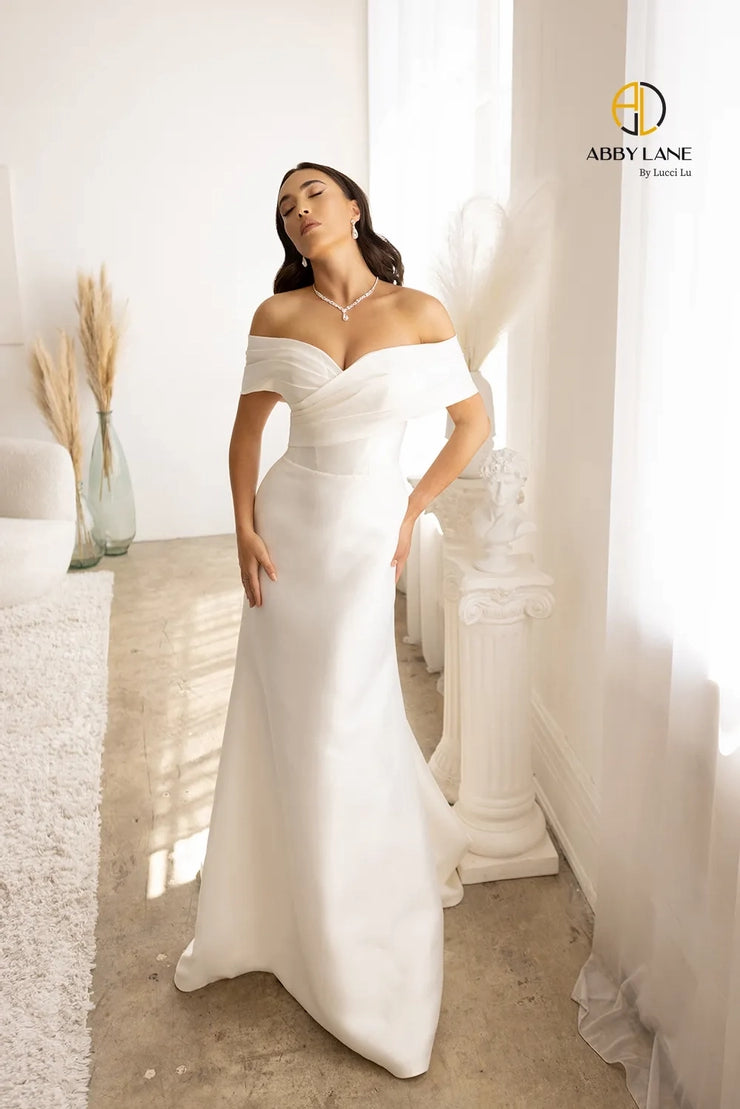 Crafted with Satin and lace, the Abby Lane Bridal 97179 Ivory Gown is a stunningly beautiful A-Line dress with wide, off the shoulder straps. Its train is delicately trimmed with lace for a sophisticated look. Perfect for the special day.  Color:  Ivory