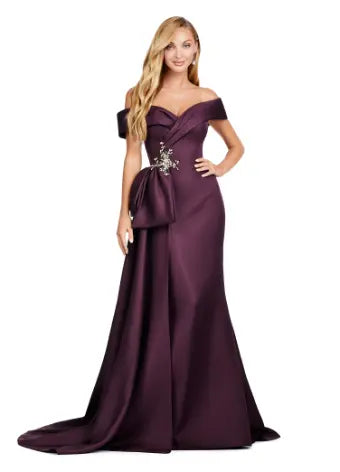 This Ashley Lauren 11425 Long Wine Evening Mother of Dress is the perfect choice for any formal occasion. The off-shoulder design adds a touch of elegance, while the fitted satin fabric hugs your figure for a flattering silhouette. The overskirt adds a dramatic flare, making you feel like a pageant queen. Elevate your style with this versatile and stunning dress. An elegant off the shoulder neckline drapes the shoulders in elegant evening gown. The look is complete with beaded details and a side overskirt.