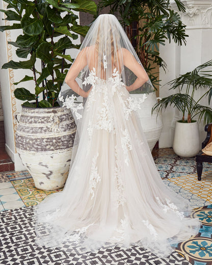 Dreamy BL354 is for the modern bride seeking a touch of natural charm. Detailed floral lace appliqués decorate the bodice, supported by classic spaghetti straps and a plunging V-neckline. V-cutouts on the sides of the bodice show a subtle amount of skin, complemented by a low V-back. The soft tulle skirt is ethereal as can be, lace appliqués interspersing throughout and cascading into a 65 inch train