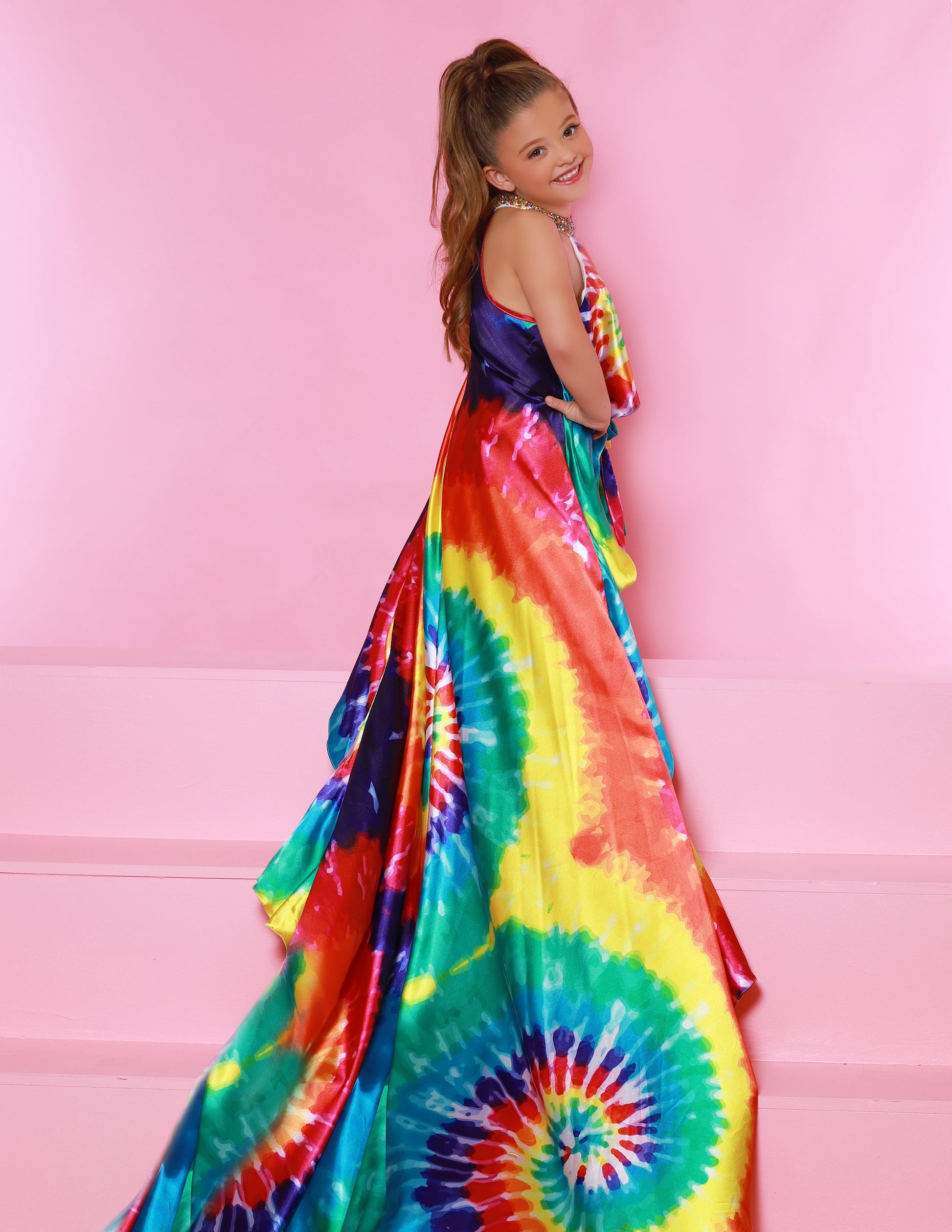 Sugar Kayne C159 is a two piece fun fashion Tie Dye Girls Pageant Wear Featuring an embellished choker high neckline flowing into a long train.  Colors:  Tie Dye  Sizes:  2-16  (Sizes 2-6 do not have bust cups, Sizes 8-16 will have preteen size bust cups)
