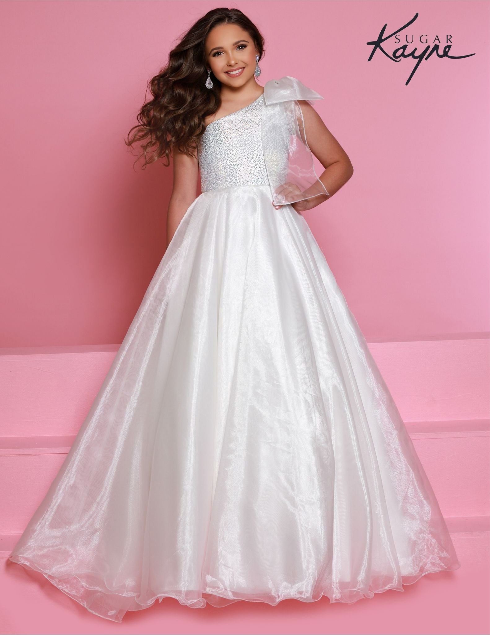 Sugar Kayne C310 Girls and Preteens One Shoulder bodice with a Bow on the shoulder A Line Shimmer Pageant Dress Crystal Gown&nbsp;
Go ahead and take a BOW in this lovely one-shoulder organza ballgown. The ombre beaded bodice brings all the dazzle!

Colors:
Orange, Yellow, Blue, White, Neon Pink

Sizes:
2, 4, 6, 8, 10, 12, 14, 16

Fabric Organza, Mesh, Satin Lining

(Sizes 2-6 do not have bust cups, Sizes 8-16 will have preteen size bust cups)