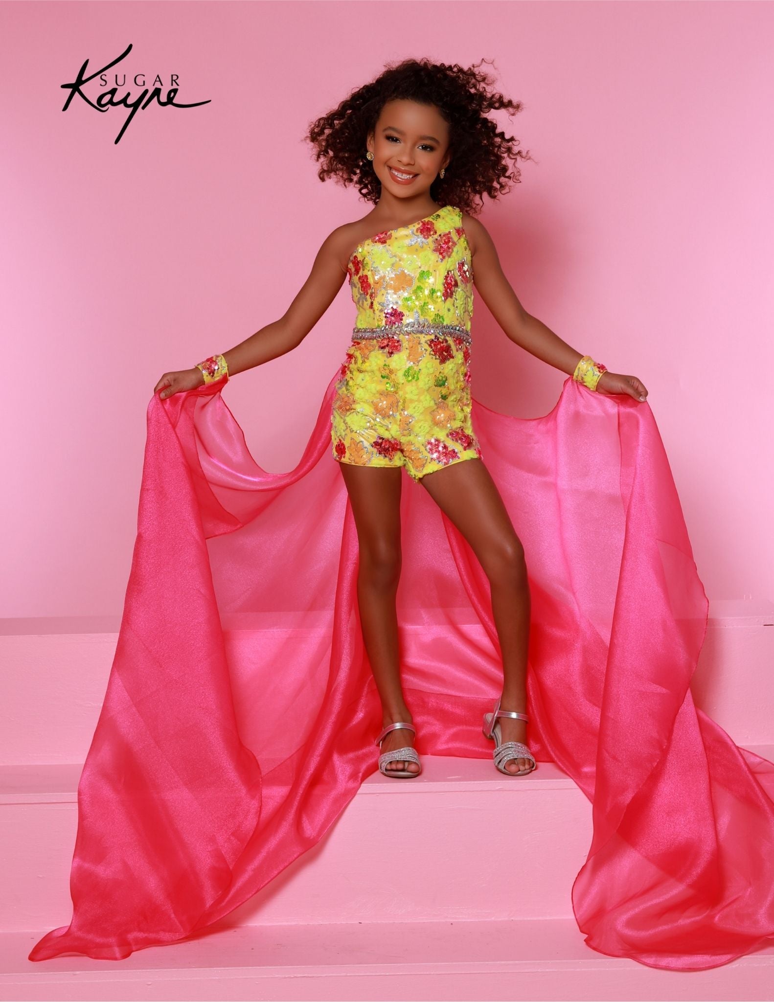 The Sugar Kayne C347 is a fun, fashion shimmer girls pageant romper with a sequins mesh overskirt. It's designed with soft and comfortable material, perfect for any special occasion.&nbsp;Shine bright on stage with our Sequin Mesh Romper and Shimmer Organza Overskirt! This romper is designed for those girls who love to sparkle and own the stage!

Color:&nbsp;Bluetiful, Lemon Burst

Size:&nbsp;2, 4, 6, 8, 10, 12, 14, 16

Fabric:&nbsp;Sequin Stretch Mesh, Metallic Jersey Lining, Shimmer Organza

(Sizes 2-6 do