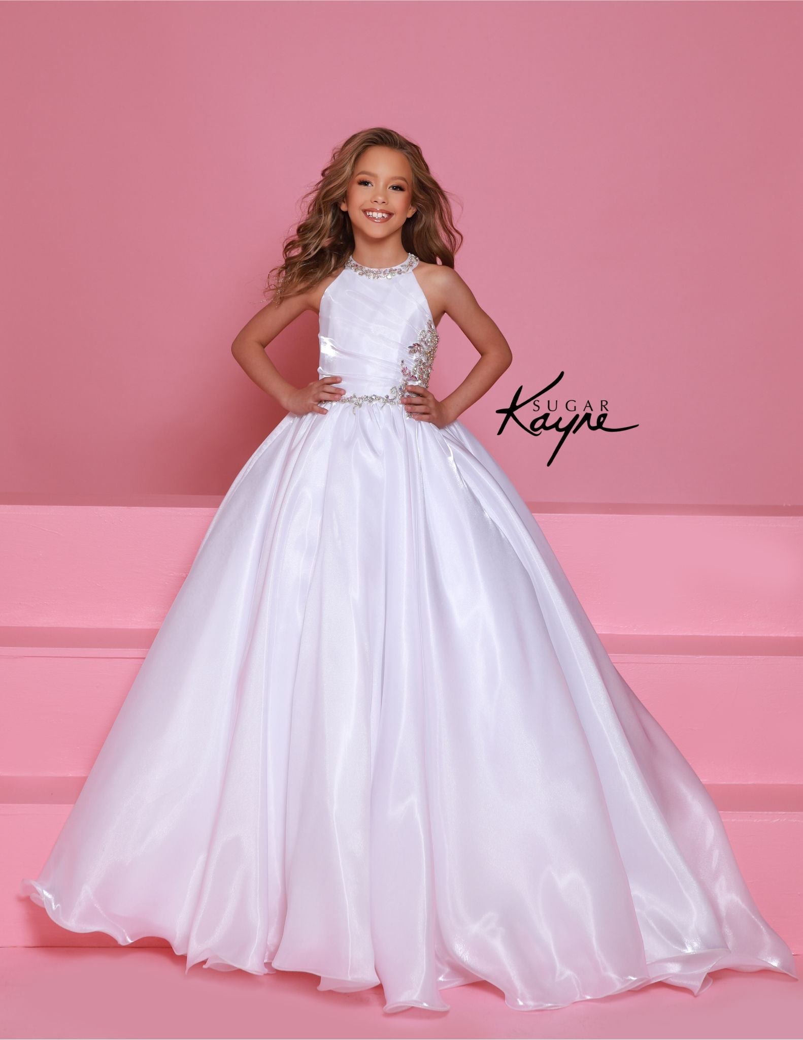 This stunning Sugar Kayne C379 pageant dress features a high neck and A-line design with shimmering beaded details. The elegant ballgown silhouette is perfect for any formal event, ensuring your little girl looks and feels like a princess. Make a statement with this beautiful and eye-catching dress. Step into the spotlight and embody the dazzling diva within! This mirror organza ballgown, with its elegant halter-style neckline, guarantees you’ll captivate the audience with both grace and style.&nbsp;

Sizes