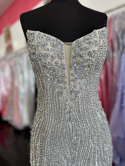 This expertly crafted Chic and Holland HF110284 gown in size 0 features a stunning silver crystal embellishment that elevates the fitted silhouette. Designed with a high slit, it offers graceful movement and a striking profile. The illusion scoop neck gracefully transitions into a V-neckline, combining elegance with modern couture appeal. Perfect for pageants or formal events, this gown balances sophistication and glamour to ensure unforgettable presence.

Size 0&nbsp;

Color: Silver