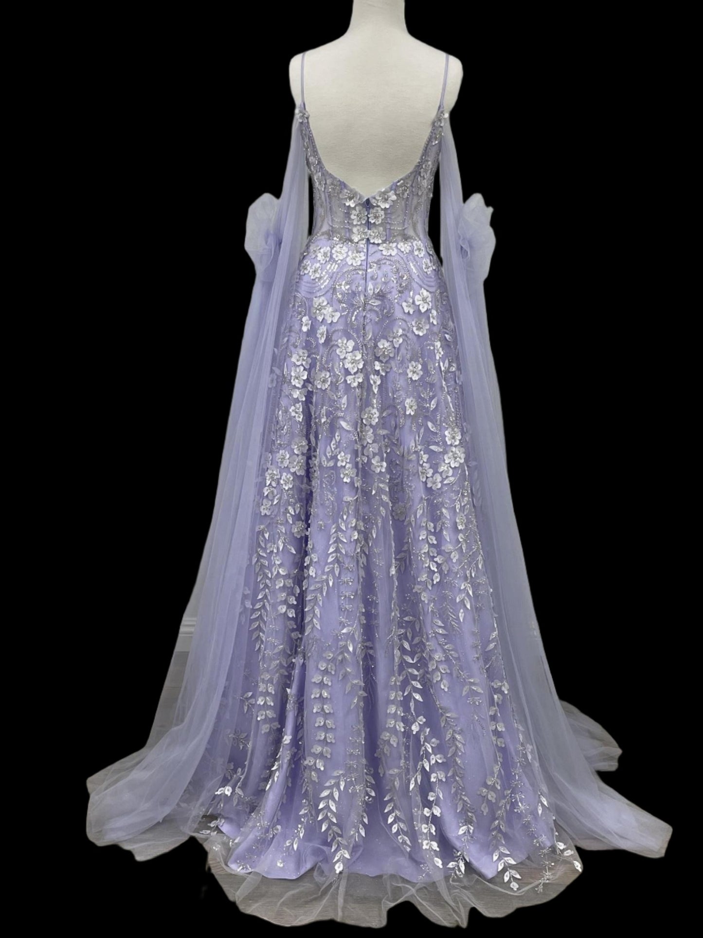 Elevate your formal wear with the Nox Anabel E1281 Sheer Corset Cape Formal Dress. The size 6 lilac dress features exquisite beadwork and a flattering A-line silhouette. The sheer corset top adds a touch of elegance, while the lace details complete the look. Perfect for any special occasion, this dress is a must-have for fashion-forward individuals. Scoop neck  Size: 6  Color: Lilac