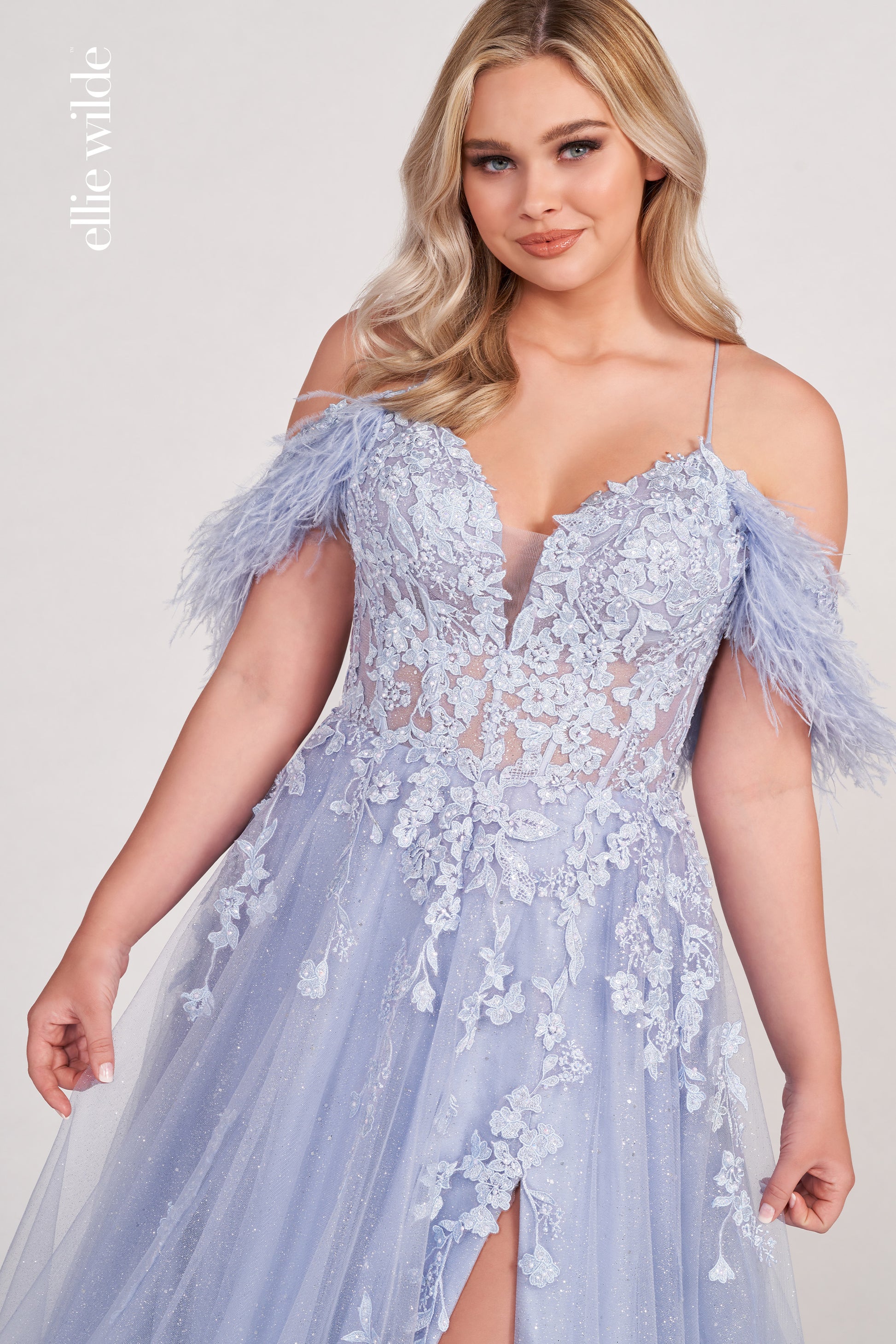 The Ellie Wilde EW34066 is a stunning A-line gown with a sheer sequin corset and feather off-the-shoulder detail. Boasting a dazzling shimmer finish and dramatic slit, this exquisite dress will make you the belle of the ball.  Sizes: 00-16  Colors: ORANGE, RED, PERIWINKLE, IRIS