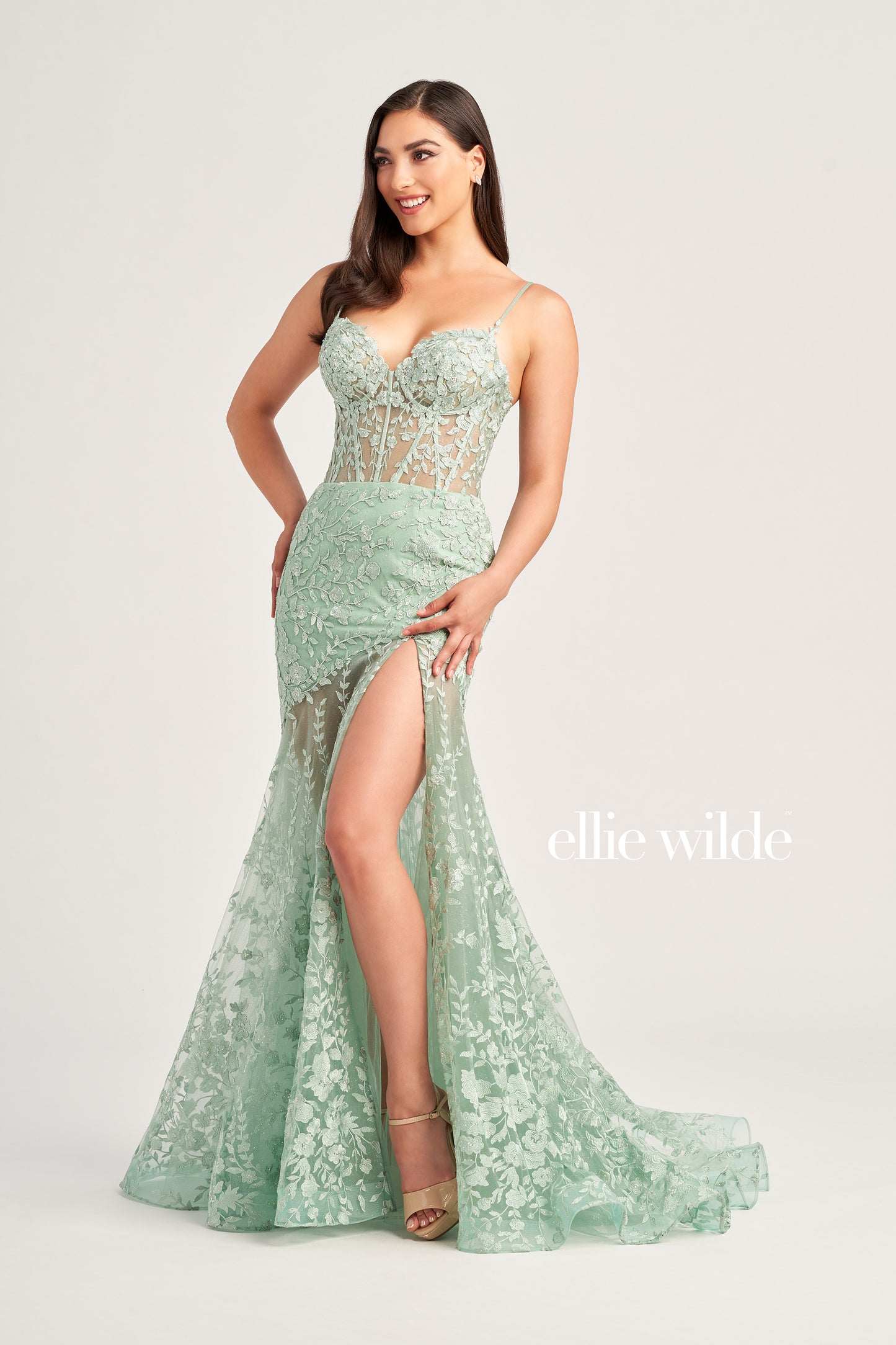 This Ellie Wilde EW35005 Sheer Corset Shimmer Lace Slit Prom Dress Formal Gown adds an elegant touch to formal events. Featuring a sheer corset with shimmer lace and an asymmetrical sheer skirt train, this gorgeous gown will make you stand out. Perfect for the special night.  COLOR: RED, LIGHT YELLOW, LIGHT BLUE, MAGENTA, ROYAL BLUE, EMERALD/NUDE, SAGE SIZE: 00 - 16