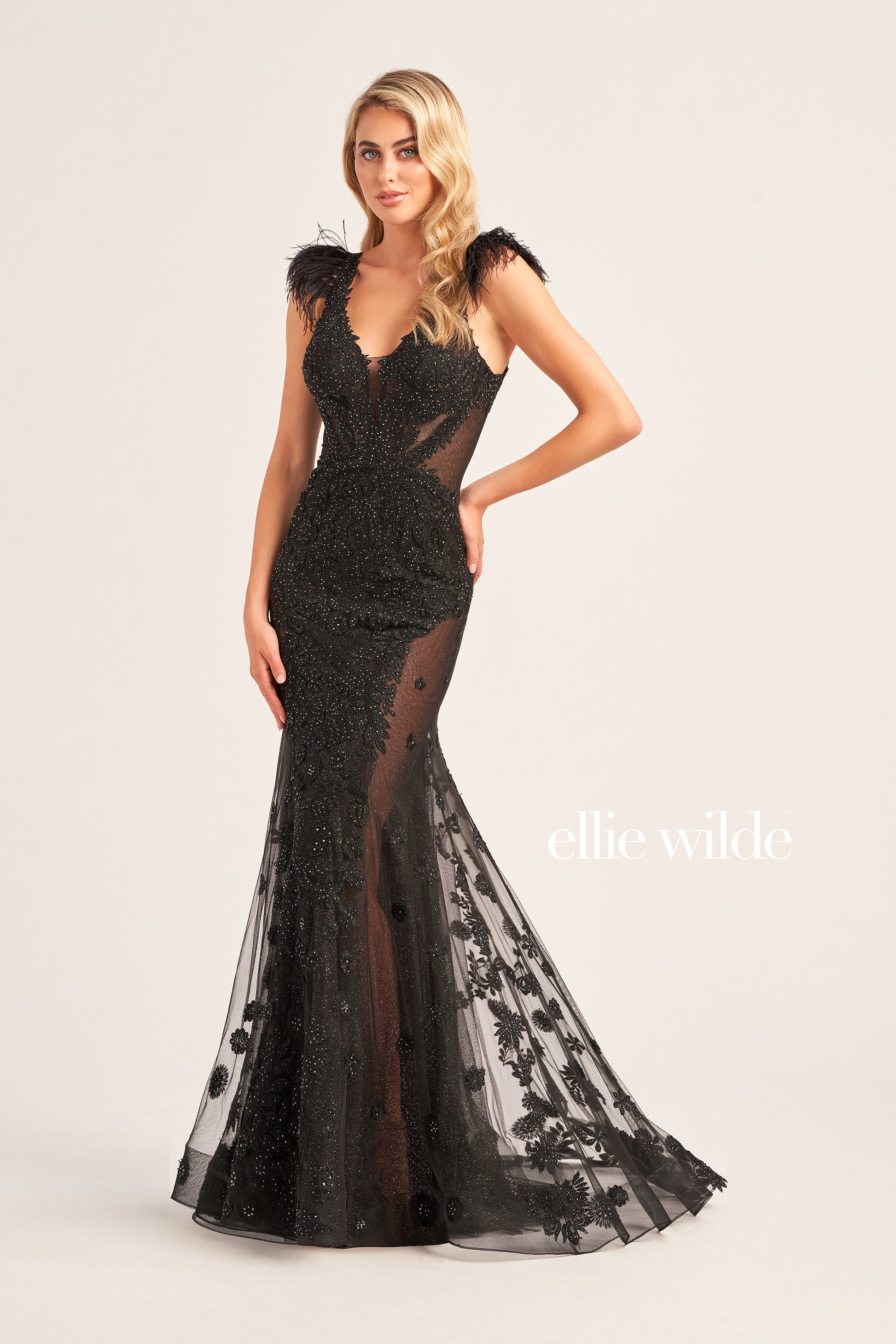 Look dazzling in this Ellie Wilde EW35009 evening gown, crafted with glitter tulle, lace appliques, and stone accents for an eye-catching look. A plunging V-neck, long trumpet silhouette, and detachable feather cap sleeves add to the glamour. The natural waistline and side mesh inset complete the look.  COLOR: BLACK, EMERALD, SAGE, STRAWBERRY, BLUEBELL SIZE: 00 - 20