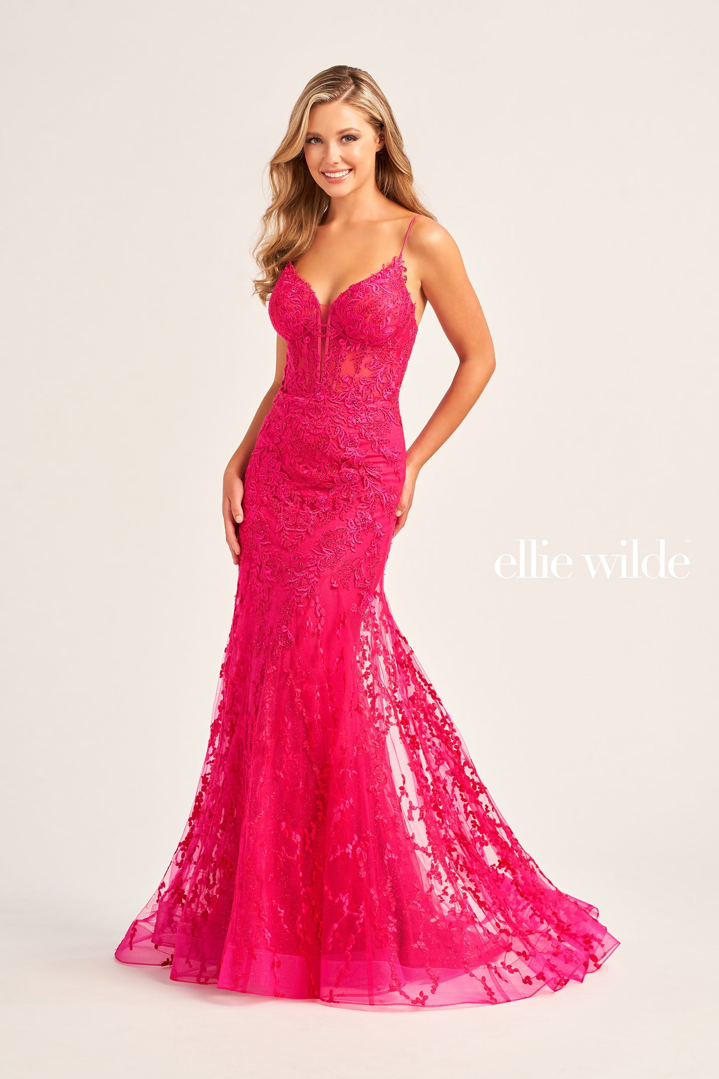 The Ellie Wilde EW35010 dress features a plunging sweetheart neckline, corset bodice, and lace-up back to flatter your figure while adding a touch of sophistication. Crafted from shimmering tulle, glitter tulle, lace, and embellished with stone accents, this long trumpet silhouette is perfect for making a statement on your special day. Plus, this dress is designed with a natural waistline for comfort.  COLOR: BLACK, ORANGE, LIGHT YELLOW, MAGENTA, EMERALD, ROYAL BLUE, SAGE, STRAWBERRY SIZE: 00 - 20