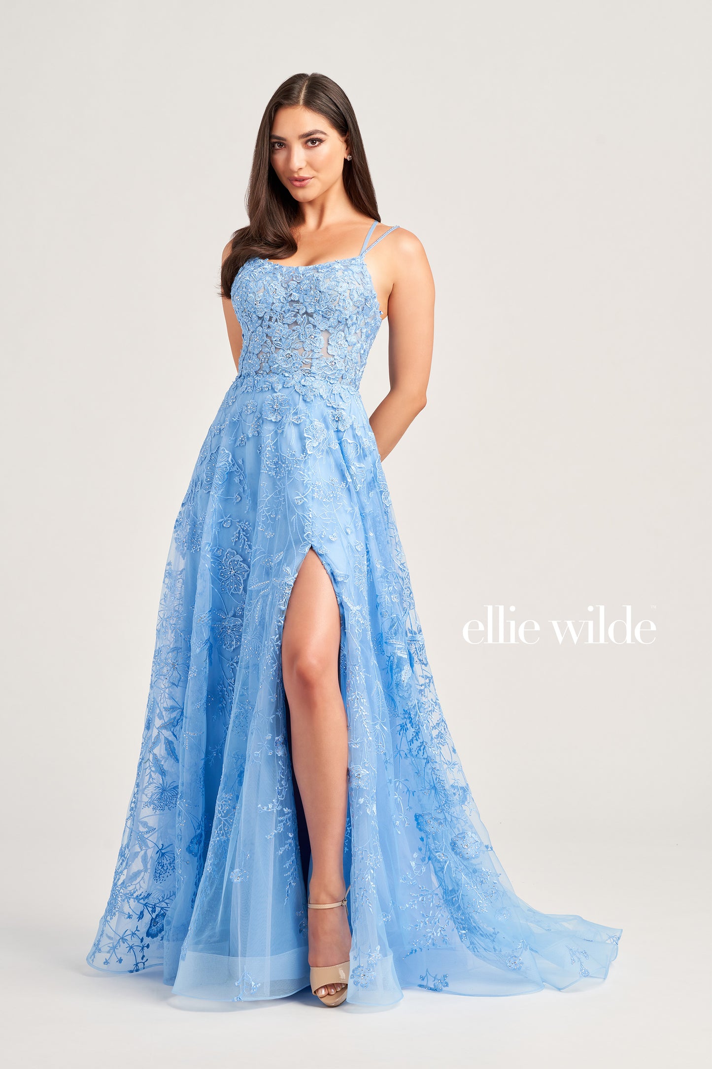 This Ellie Wilde EW35012 Formal Gown is the perfect blend of style and comfort. Crafted with beautiful embroidered tulle, lace, and stone accents, this dress features a long length, scoop neckline, and A-line silhouette. Practical and eye-catching, this gown has pockets, a high slit, and a lace-up back, all draped on a flattering natural waistline. A perfect pick to shine in style at your next event.  COLOR: MAGENTA, EMERALD, STRAWBERRY, BLUEBELL SIZE: 00 - 24