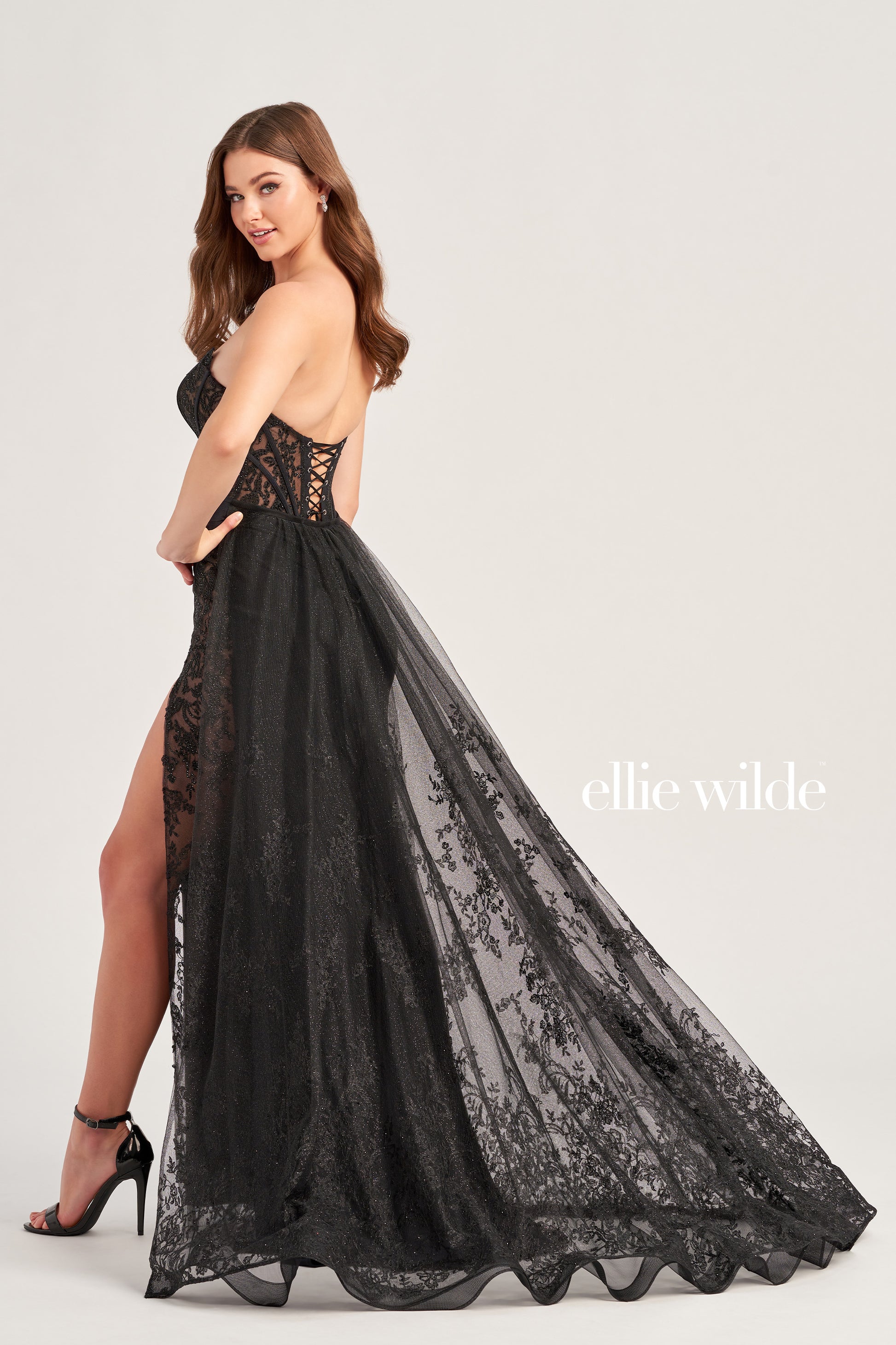 Be prepared to stun in this Ellie Wilde EW35032 long prom dress. Featuring a scoop neckline, glitter lace and stone accents, with a lace up grommet back and high slit for added flair. The corset bodice and detachable train ensure you make a statement. Crafted with stretch jersey for a comfortable fit-and-flare silhouette.  COLOR: BLACK, EMERALD, ROYAL BLUE, RUBY, IRIS, WHITE