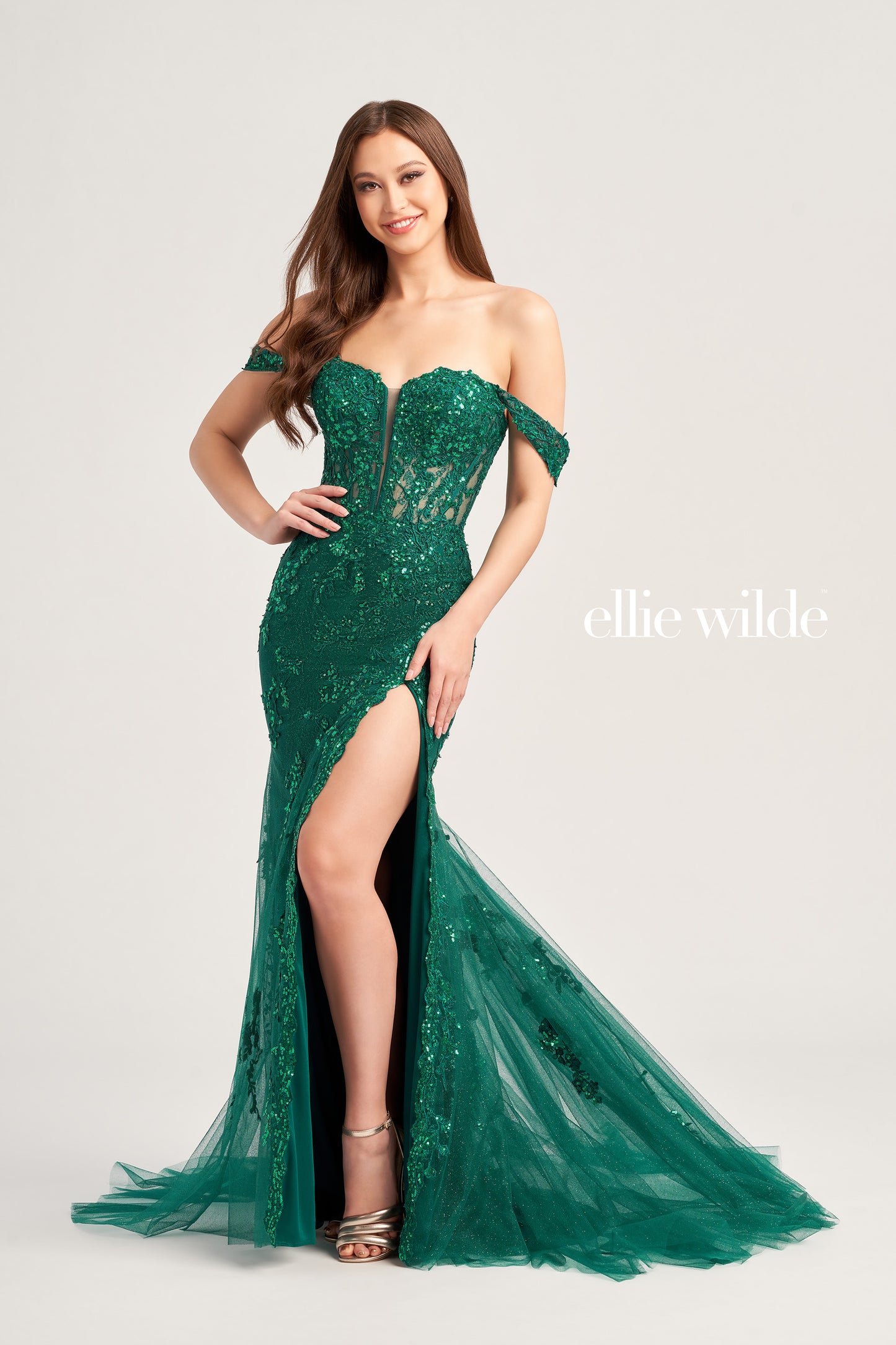 Make a big splash in this Ellie Wilde EW35082 Sheer Sequin Corset Shimmer Prom Dress. Featuring a sheer corset bodice, fit and flare silhouette and mermaid skirt with high slit, this show-stopping design is sure to turn heads. Detachable draped shoulder straps, sweetheart neckline and sequin fabric complete this glamorous look. Exquisite lace appliques and glitter tulle with separate spaghetti straps add the perfect touch.  COLOR: RED, MIDNIGHT, EMERALD, LILAC SIZE: 00 - 16