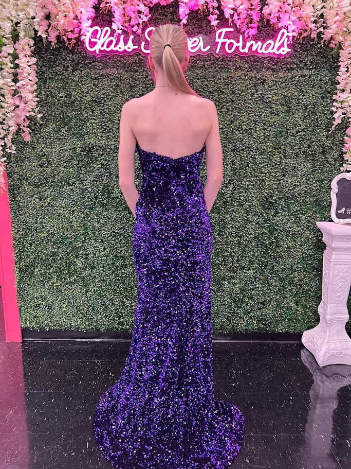 Step into the spotlight with the Lucci Lu 1332 Sequin Velvet Strapless Formal Pageant Dress. This stunning gown features a crystal-embellished bodice and a high slit for added drama. The strapless peak point neckline adds a touch of elegance, making it the perfect choice for your next formal event or prom night.  Sizes: 0-18  Colors: Purple, Magenta, Royal Blue, Silver