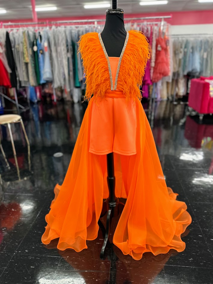 Marc Defang's 8308 showcases expert pageant design in size 12, featuring a striking orange romper paired with an elaborate feathered overskirt. This sophisticated ensemble balances practicality with theatrical impact—the fitted romper provides stability and comfort during competition, while the cascading feather overlay delivers the glamorous presence judges expect. The vibrant orange hue commands attention under stage lighting, and the feather detailing adds dimension and movement with every step. An excel