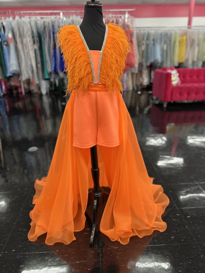 Marc Defang's 8308 showcases expert pageant design in size 12, featuring a striking orange romper paired with an elaborate feathered overskirt. This sophisticated ensemble balances practicality with theatrical impact—the fitted romper provides stability and comfort during competition, while the cascading feather overlay delivers the glamorous presence judges expect. The vibrant orange hue commands attention under stage lighting, and the feather detailing adds dimension and movement with every step. An excel