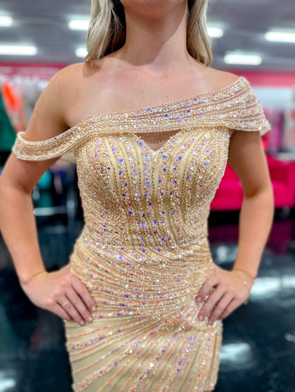 The Nox Anabel H1669 in size 4 is a meticulously crafted champagne-colored gown designed for formal occasions. Its long, fitted silhouette is enhanced by detailed beadwork and sequins, offering a refined shimmer that catches the light elegantly. The gown features a sophisticated slit, providing both movement and subtle allure. A standout element is the detachable asymmetrical off-the-shoulder cape sleeve, which adds versatility and a modern edge to the classic design. This dress combines expert tailoring wi