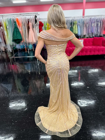 The Nox Anabel H1669 in size 4 is a meticulously crafted champagne-colored gown designed for formal occasions. Its long, fitted silhouette is enhanced by detailed beadwork and sequins, offering a refined shimmer that catches the light elegantly. The gown features a sophisticated slit, providing both movement and subtle allure. A standout element is the detachable asymmetrical off-the-shoulder cape sleeve, which adds versatility and a modern edge to the classic design. This dress combines expert tailoring wi