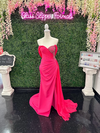 The Lucci Lu 1348 Pageant Dress is a stunning style for any special occasion. It features a fuchsia corset wrap, off the shoulder design that softly drapes around the back of the arms.  slit skirt with a chiffon overskirt. This size 4 dress will surely make you stand out. boning in corset style bodice with detailed beading and crystals  Size: 4  Color: Fuchsia