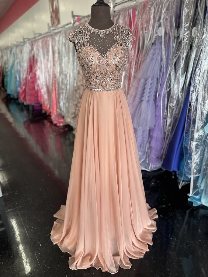 Elevate your formal occasion with the Johnathan Kayne 2750, a size 4 charcoal A-line gown designed for timeless elegance. Featuring a beaded high neckline and delicate cap sleeves, this dress combines refined detailing with a flowing chiffon train for graceful movement. Perfect for the mother of the bride or any distinguished event, it offers a sophisticated silhouette that enhances your presence with understated glamour.

Size: 4

Color: Blush