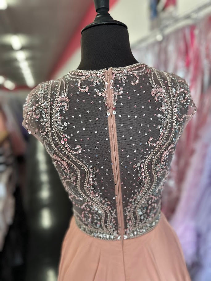 Elevate your formal occasion with the Johnathan Kayne 2750, a size 4 charcoal A-line gown designed for timeless elegance. Featuring a beaded high neckline and delicate cap sleeves, this dress combines refined detailing with a flowing chiffon train for graceful movement. Perfect for the mother of the bride or any distinguished event, it offers a sophisticated silhouette that enhances your presence with understated glamour.

Size: 4

Color: Blush