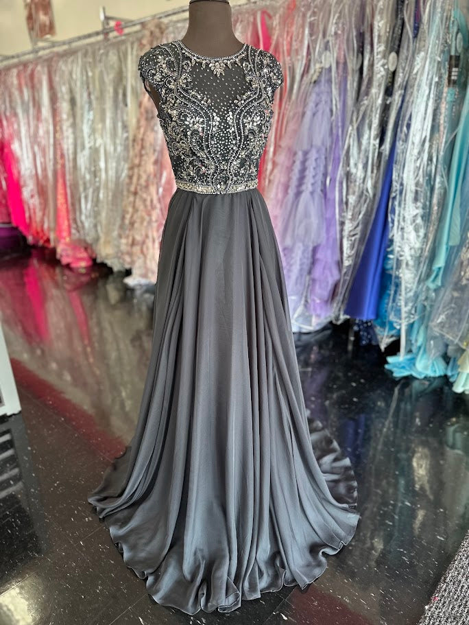 Elevate your formal occasion with the Johnathan Kayne 2750, a size 4 charcoal A-line gown designed for timeless elegance. Featuring a beaded high neckline and delicate cap sleeves, this dress combines refined detailing with a flowing chiffon train for graceful movement. Perfect for the mother of the bride or any distinguished event, it offers a sophisticated silhouette that enhances your presence with understated glamour.

Size: 4

Color: Charcoal