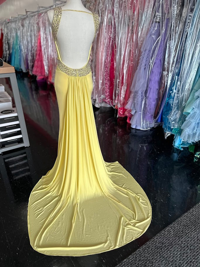 Jovani JVN93211 is a stunning Long Fitted Jersey Formal evening gown. Featuring a high Crystal Embellished Neckline and pleated bust with an asymmetrical bandage wrapped waist. This stunning Prom &amp; Pageant gown features a Slit in the skirt and sweeping train.

Available Size: 2

Available Color: Yellow