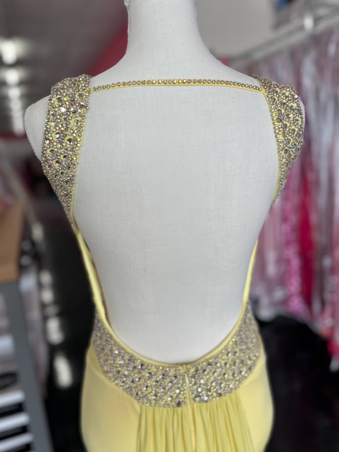 Jovani JVN93211 is a stunning Long Fitted Jersey Formal evening gown. Featuring a high Crystal Embellished Neckline and pleated bust with an asymmetrical bandage wrapped waist. This stunning Prom &amp; Pageant gown features a Slit in the skirt and sweeping train.

Available Size: 2

Available Color: Yellow