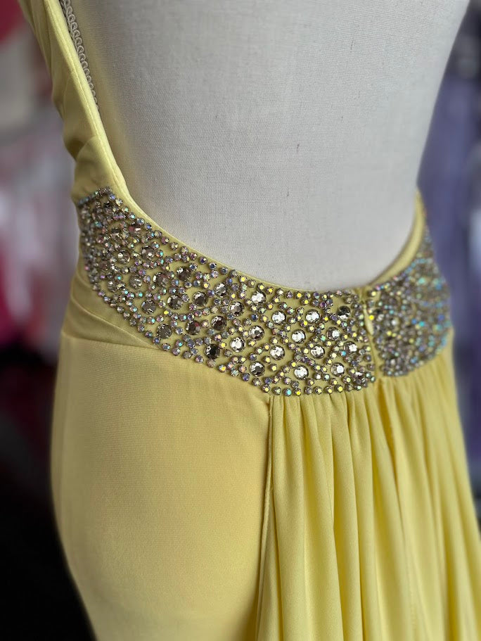 Jovani JVN93211 is a stunning Long Fitted Jersey Formal evening gown. Featuring a high Crystal Embellished Neckline and pleated bust with an asymmetrical bandage wrapped waist. This stunning Prom &amp; Pageant gown features a Slit in the skirt and sweeping train.

Available Size: 2

Available Color: Yellow