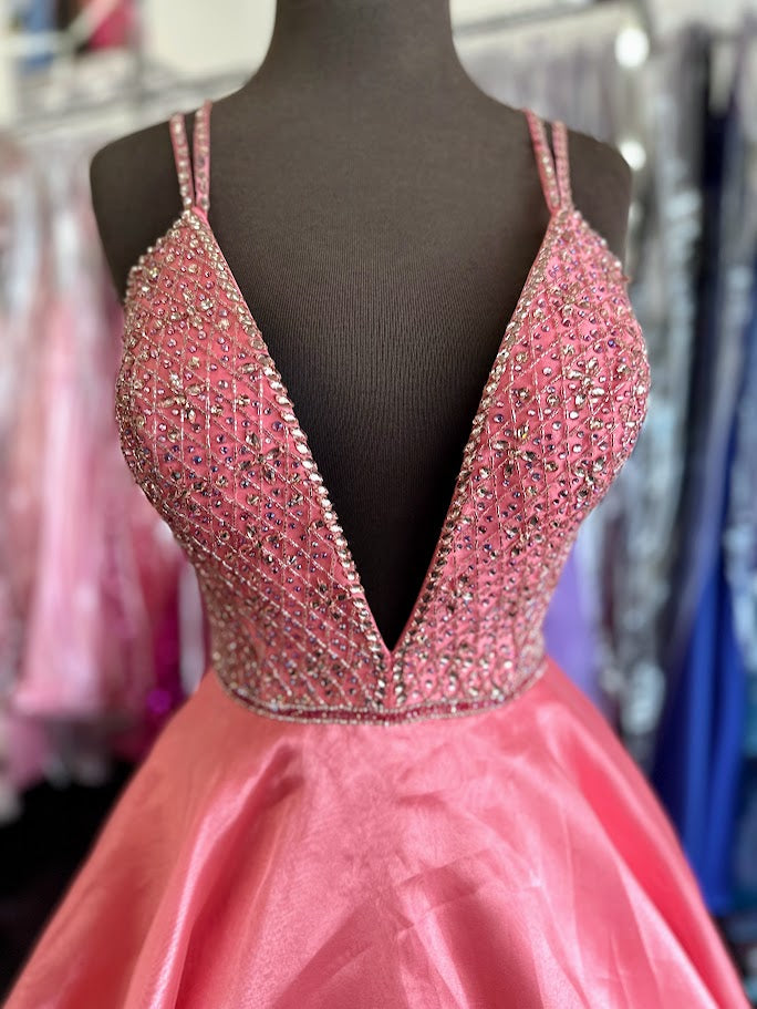 Elevate your prom night with the Johnathan Kayne 7219 long ballgown in a stunning coral hue. This size 4 dress features a graceful A-line silhouette complemented by a crystal-embellished V-neck, adding refined sparkle. Practical side pockets blend seamlessly into the design, offering convenience without sacrificing elegance. Perfect for making a memorable entrance with timeless sophistication.

Size: 4

Color: Coral