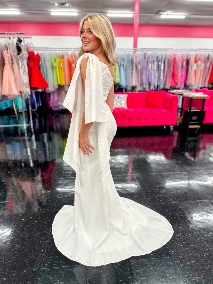 This elegant Johnathan Kayne dress in size 4 features a long ivory crepe silhouette that combines sophistication with subtle drama. Detailed with delicate beaded sequins, it offers a refined shimmer, while the slit adds a modern edge. Draped sleeves and a tasteful bow accentuate the design, creating a balanced look of grace and contemporary style—ideal for formal occasions where expert craftsmanship and timeless elegance are paramount. One Shoulder. *One of A Kind!

Size: 4

Color: Ivory