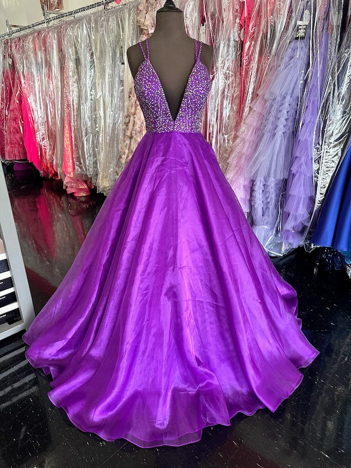 Elevate your prom night with the Johnathan Kayne 7219 long ballgown in a stunning coral hue. This size 4 dress features a graceful A-line silhouette complemented by a crystal-embellished V-neck, adding refined sparkle. Practical side pockets blend seamlessly into the design, offering convenience without sacrificing elegance. Perfect for making a memorable entrance with timeless sophistication.

Size: 4

Color: Purple