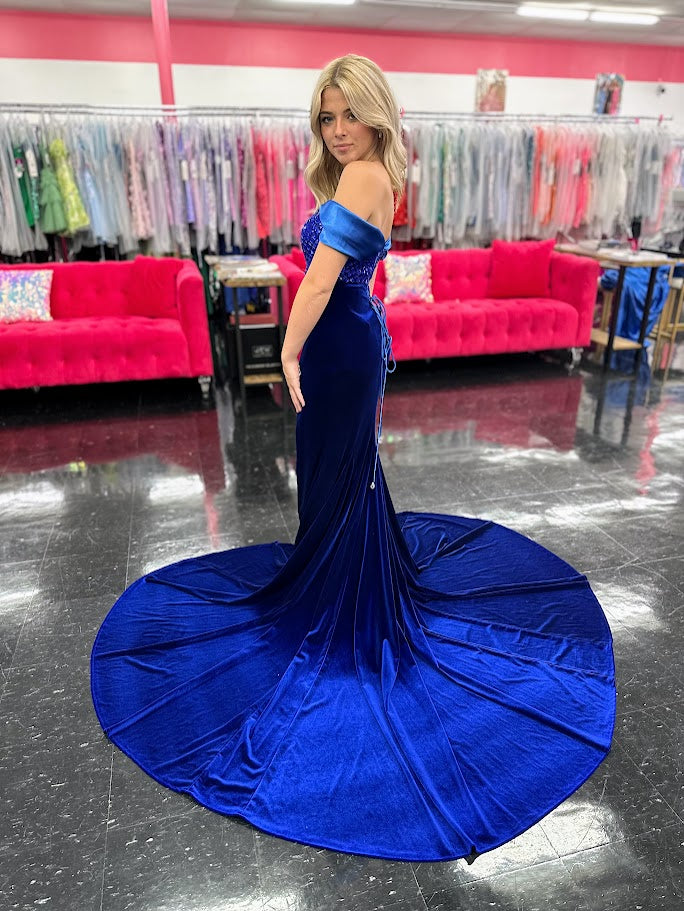 This Johnathan Kayne 2725 gown combines luxurious velvet with elegant satin details for a striking pageant look. The fitted silhouette features a straight neckline and a crystal-beaded bodice that adds refined sparkle. Detachable off-the-shoulder satin sleeves offer versatile styling, while the long satin overskirt and corset lace-up back with crystal tassels enhance both drama and fit. A tasteful slit completes this sophisticated design, perfect for making a memorable impression.

Size: 4&nbsp;

Color: Roy