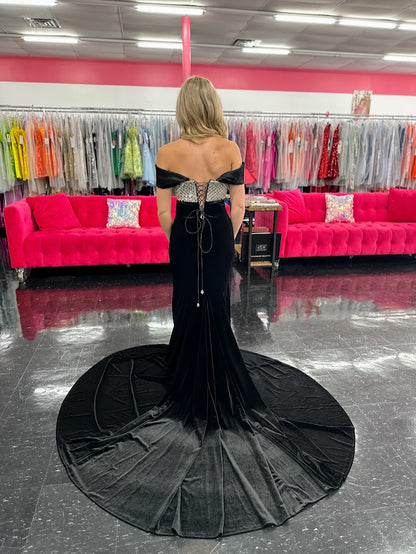 This Johnathan Kayne 2725 gown combines luxurious velvet with elegant satin details for a striking pageant look. The fitted silhouette features a straight neckline and a crystal-beaded bodice that adds refined sparkle. Detachable off-the-shoulder satin sleeves offer versatile styling, while the long satin overskirt and corset lace-up back with crystal tassels enhance both drama and fit. A tasteful slit completes this sophisticated design, perfect for making a memorable impression.

Size: 4&nbsp;

Color: Bla