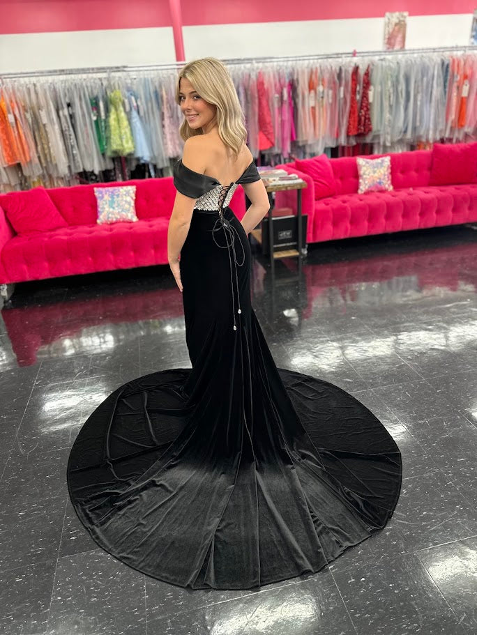 This Johnathan Kayne 2725 gown combines luxurious velvet with elegant satin details for a striking pageant look. The fitted silhouette features a straight neckline and a crystal-beaded bodice that adds refined sparkle. Detachable off-the-shoulder satin sleeves offer versatile styling, while the long satin overskirt and corset lace-up back with crystal tassels enhance both drama and fit. A tasteful slit completes this sophisticated design, perfect for making a memorable impression.

Size: 4&nbsp;

Color: Bla