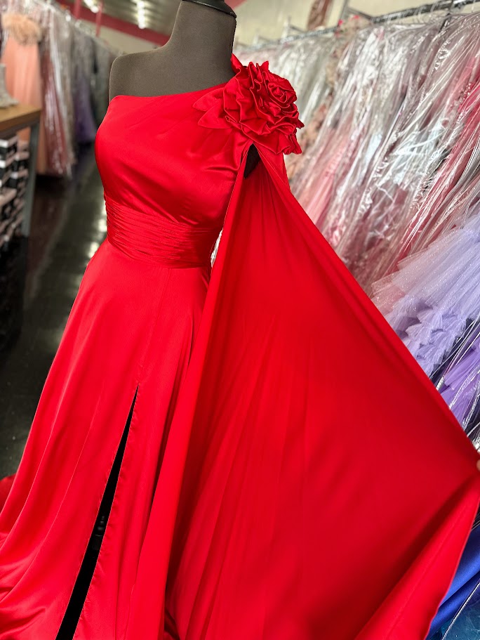 Elevate your formal occasion with this Johnathan Kayne gown, featuring a striking one-shoulder design and a flowing satin cape. The vibrant red fabric drapes elegantly, complemented by a tasteful slit and delicate floral accents. Tailored in size 4, this long dress combines classic sophistication with modern flair, perfect for pageants or special appearances.

Size: 4

Color: Red