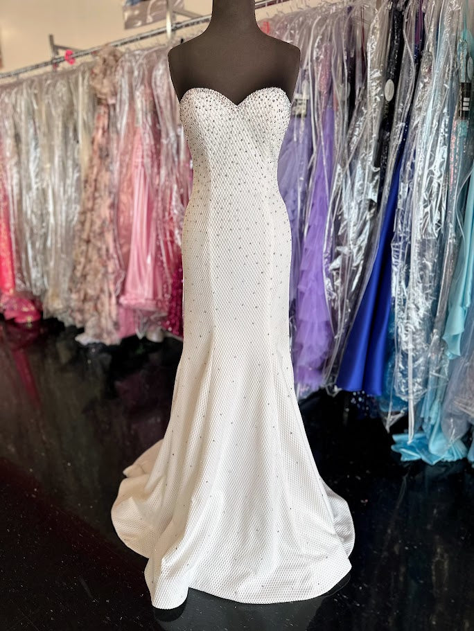 Elevate your evening with this exquisite Jovani 33132 mermaid gown in pristine white. Designed in a size 4, this long prom dress features a strapless sweetheart neckline that beautifully frames the shoulders. Adorned with delicate crystal embellishments, it offers a refined sparkle perfect for pageants or formal occasions. The fitted silhouette gracefully accentuates your figure, ensuring a stunning and sophisticated presence at any event.

Size: 4

Color: White