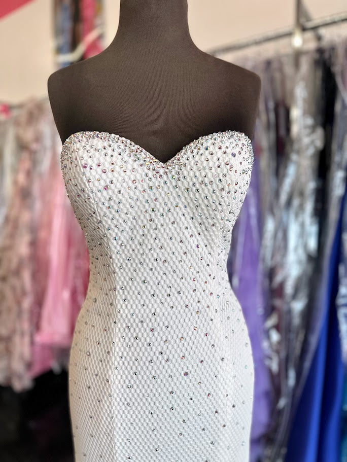 Elevate your evening with this exquisite Jovani 33132 mermaid gown in pristine white. Designed in a size 4, this long prom dress features a strapless sweetheart neckline that beautifully frames the shoulders. Adorned with delicate crystal embellishments, it offers a refined sparkle perfect for pageants or formal occasions. The fitted silhouette gracefully accentuates your figure, ensuring a stunning and sophisticated presence at any event.

Size: 4

Color: White