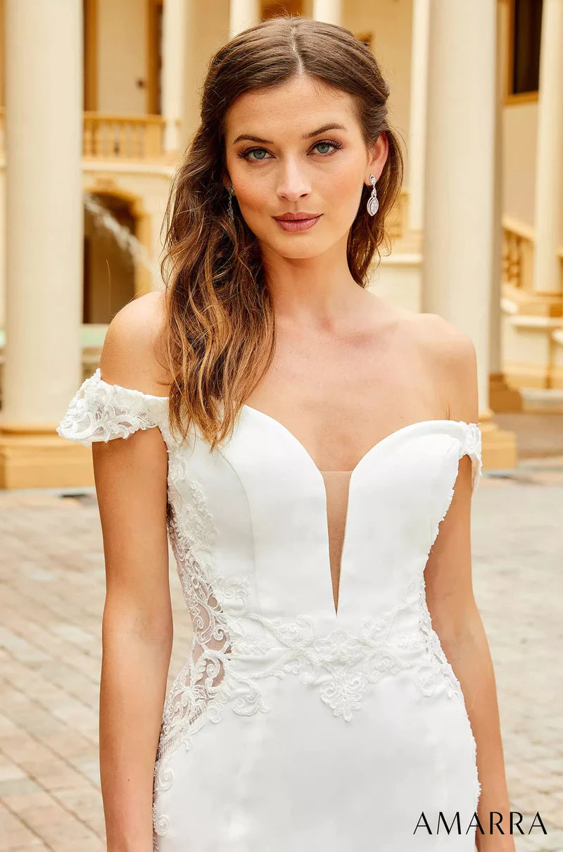 Amarra Bridal 7034 Julie Fitted Off The Shoulder Lace Up Back Plunging Neckline Floral Lace Cut-Outs Train Wedding Gown. For the glamorous and alluring bride, Julie delivers. This trumpet-style wedding dress featuring an off-the-shoulder look and lace cutouts at the side is sure to captivate