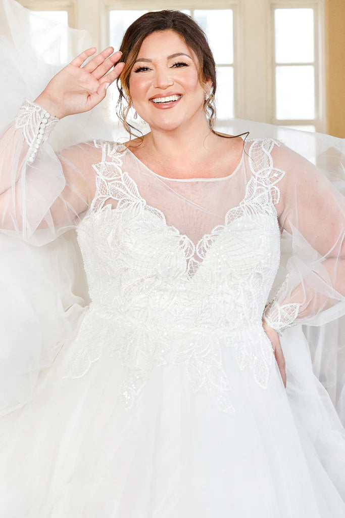 Michelle Bridal For Sydney's Closet MB2302 A-Line Silhouette Modern Leaf Appliques Clear Sequins Bugle Beads Long Sleeve Pouf Sleeves Plus Size "Seraphina" Bridal Dress.  The Michelle Bridal For Sydney's Closet MB2302 wedding dress exudes sophistication and classic elegance with its A-Line silhouette, clear sequins, bugle beads, and modern leaf appliques. Its long sleeve pouf sleeves add a contemporary touch for the perfect bridal look. Plus size available.