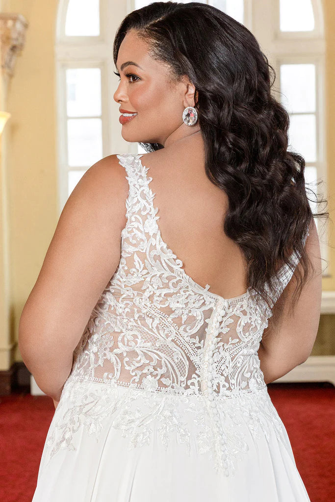 Michelle Bridal For Sydney's Closet MB2303 A-Line Modified Empire Waistline Chiffon Floral Lace With Sequins V-Neck Backless Plus Size "Radhika" Bridal Dress. The Michelle Bridal For Sydney's Closet MB2303 Radhika Dress is a stunning statement piece for special occasions. Crafted from airy chiffon and sequined lace, it features a modified empire waistline, v-neck, and backless design. The perfect mix of chic and romance, this plus-size dress is designed to flatter any figure.